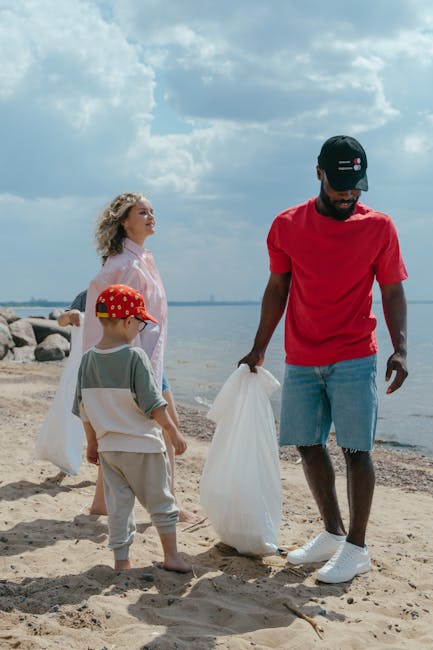 A group of black rubbish bags filled with waste are scattered across a grassy area in front of a multi-storey residential building. The bags are made of durable plastic, appear to be tightly sealed, and are positioned in various orientations on the lawn. Behind the bags, there are leafless trees with dark, textured trunks and sprawling branches that partially obscure the building’s facade. The building features large windows with white frames and a mix of panels in dark and light tones, contributing to a modern architectural style. The environment suggests an outdoor waste collection or disposal scene, possibly related to private rubbish removal services such as those provided by Rubbish Clearance Camden, as part of an alternative to council-managed rubbish disposal. Overcast lighting and a natural setting reinforce the typical context for scheduled rubbish clearance or cleanup projects in residential areas, illustrating how residents or waste management companies handle large or bulk waste on-site.